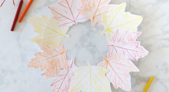 Colorful leaves arranged in a circular pattern with crayons on a marble surface